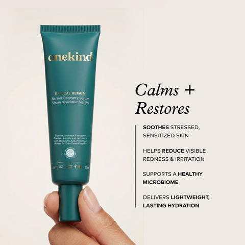 A hand holds a teal squeeze tube of Onekind Barrical Repair Barrier Recovery Serum against a light beige background, with black text on the right describing product benefits.